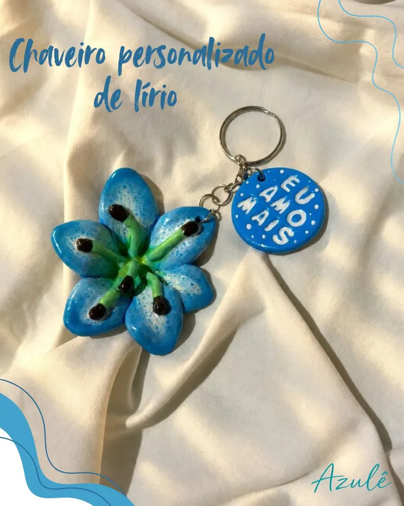 Chaveiro de lírio azul e plaquinha eu amo mais sobre tecido bege, com o título chaveiro personalizado de lírio